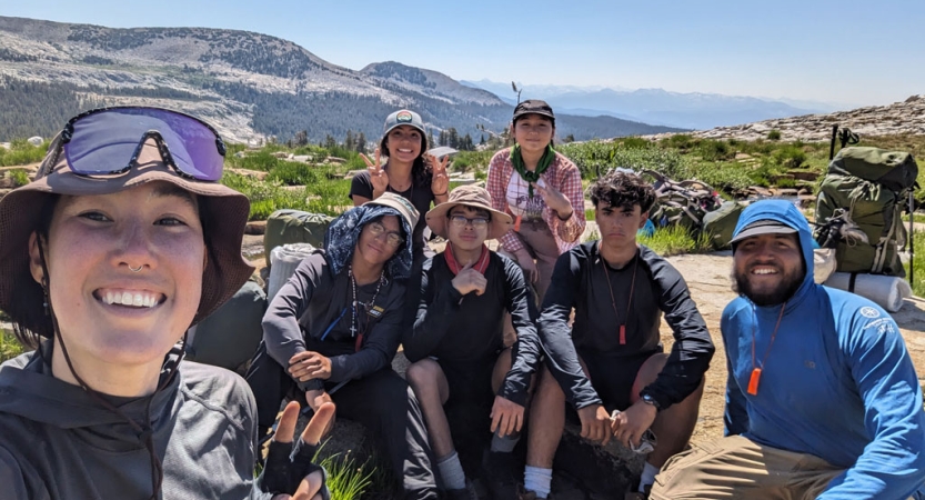 A group of people smile for a group photo in a mountain environment. 